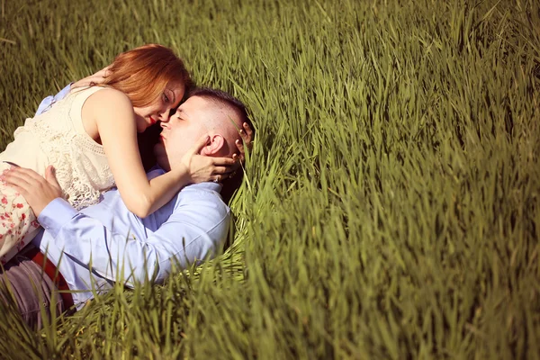 Mooie vrolijke paar liggend op groen gras — Stockfoto