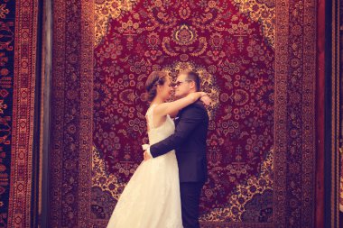 Gelin ve damat karşı asılı halı kucaklayan