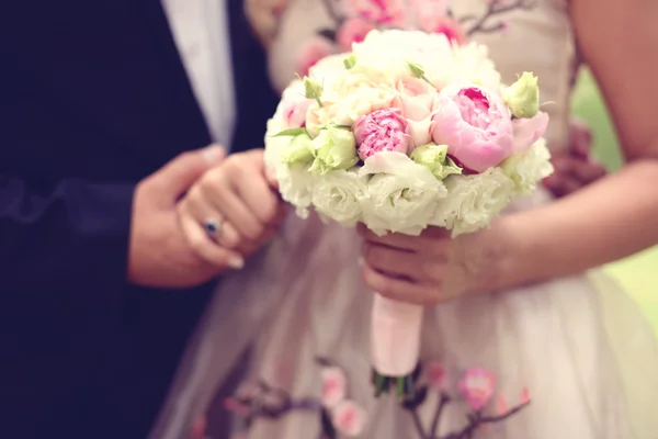 Bruden och brudgummen hand i hand. Brud holding vackra bröllop bukett — Stockfoto
