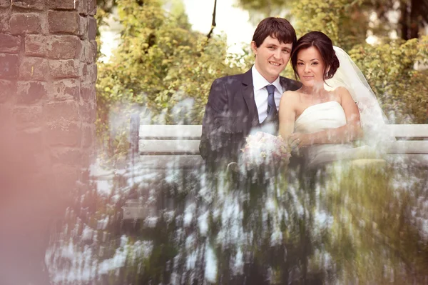 Bride and groom sitting on bench — Stock Photo, Image