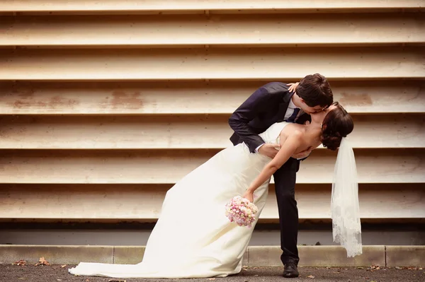 Bride and groom dancing against striped wall — Stock Photo, Image