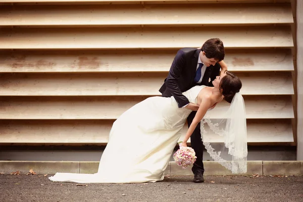 Bride and groom dancing against striped wall — Stock Photo, Image