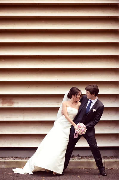 Mariée et marié dansant contre un mur rayé — Photo