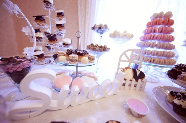 Deliciosos pasteles pequeños en mesa de boda bellamente decorada — Foto de Stock
