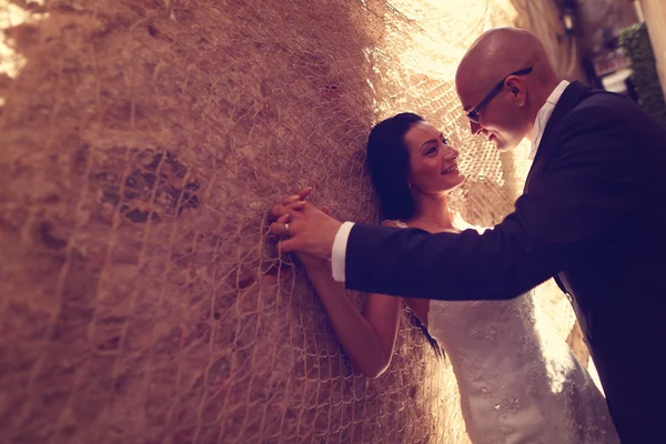 Sposa e sposo contro un muro con tramaglio — Foto Stock