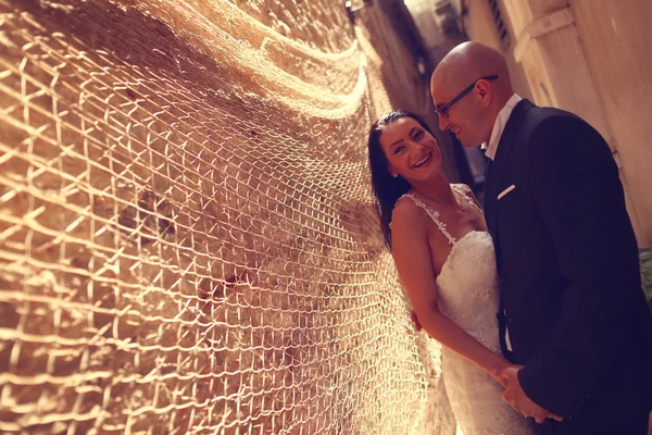 Bride and groom against a wall with trammel — Stock Photo, Image