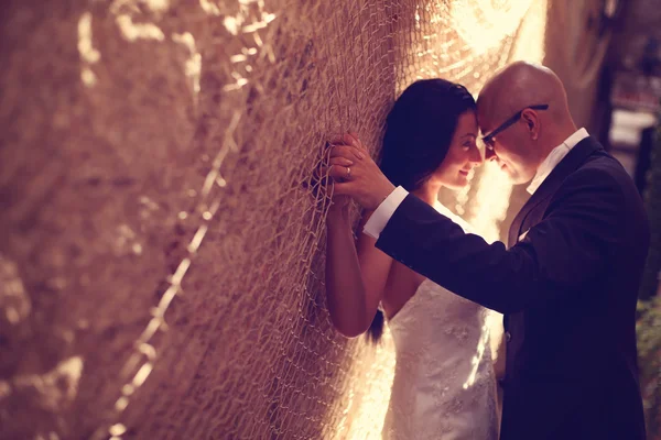 Bride and groom against a wall with trammel — Stock Photo, Image