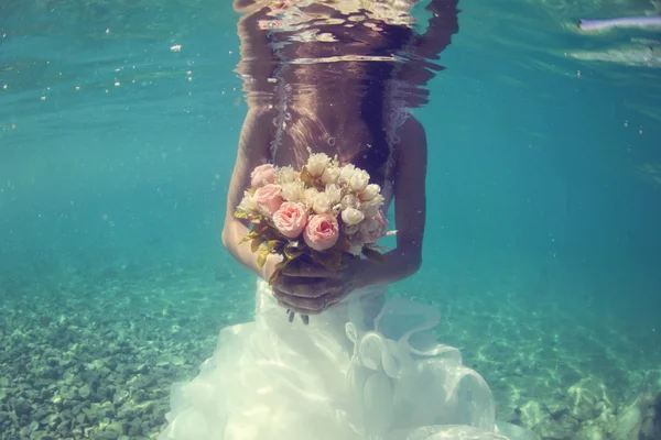 Hands of a bride holding wedding bouquet underwater — Stock Photo, Image