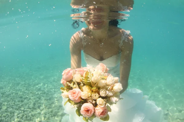 Manos de una novia sosteniendo ramo de boda bajo el agua —  Fotos de Stock