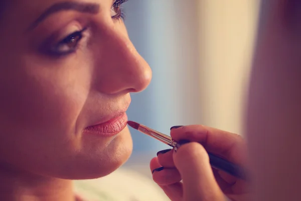 Hände der Visagistin tragen Lippenstift auf Braut auf — Stockfoto