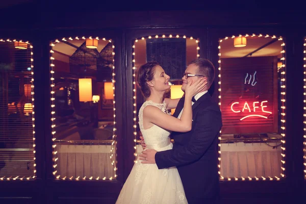 Bride and groom embracing in front of a Cafe bar — Stock Photo, Image