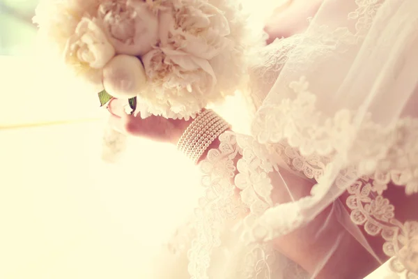 Handen van een bruid houden witte pioenrozen boeket — Stockfoto