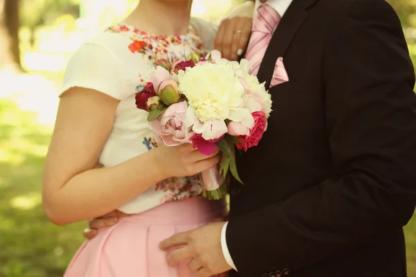 Bride holding beautiful bouquet, embracing her groom — Stock Photo, Image