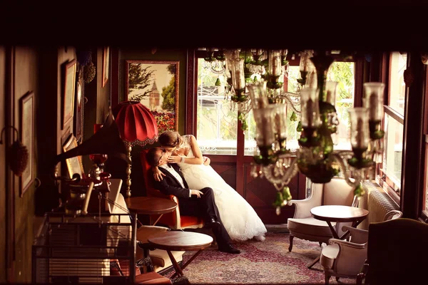 Bride and groom sitting on a chair in a beatufiul room — Stock Photo, Image