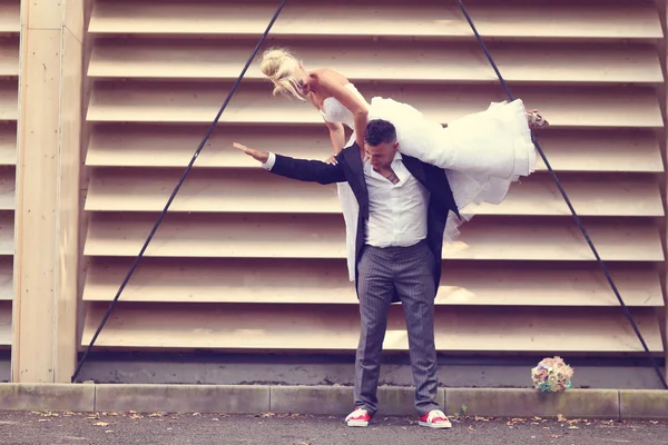 Bride and groom kissing against a striped wall — Stock Photo, Image