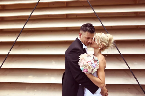 Bride and groom kissing against a striped wall — Stock Photo, Image