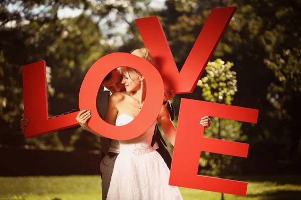 Novia y novio sosteniendo grandes cartas de amor —  Fotos de Stock