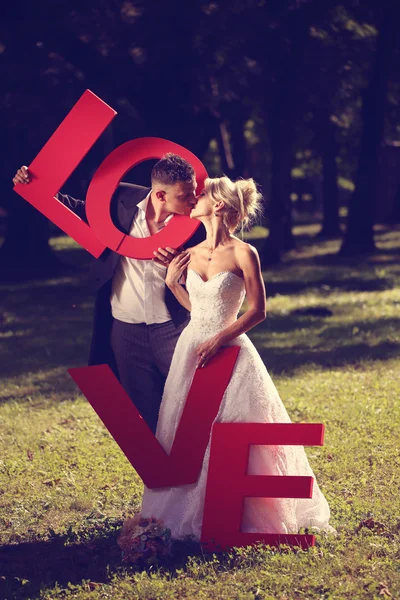 Bride and groom holding big love letters — Stock Photo, Image