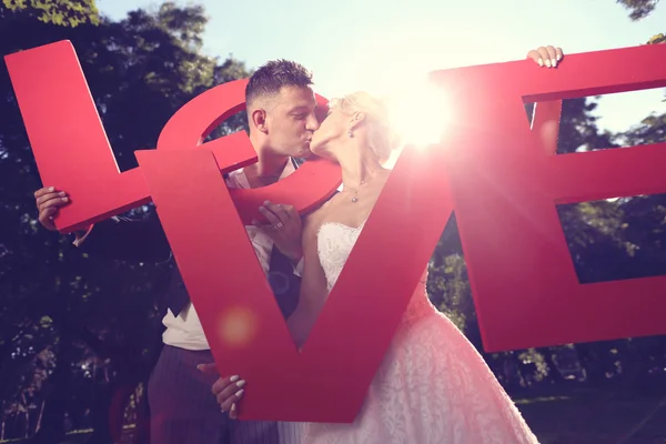 Noiva e noivo segurando grandes cartas de amor — Fotografia de Stock