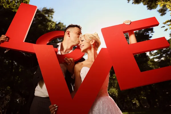 Bride and groom holding big love letters — Stock Photo, Image