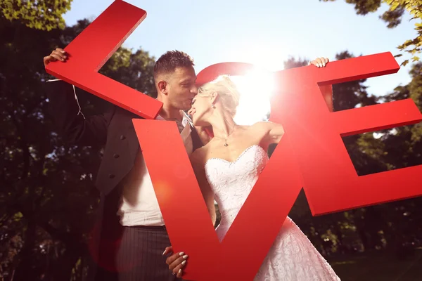 Noiva e noivo segurando grandes cartas de amor — Fotografia de Stock