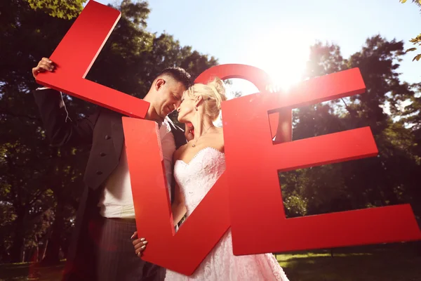 Bride and groom holding big love letters — Stock Photo, Image