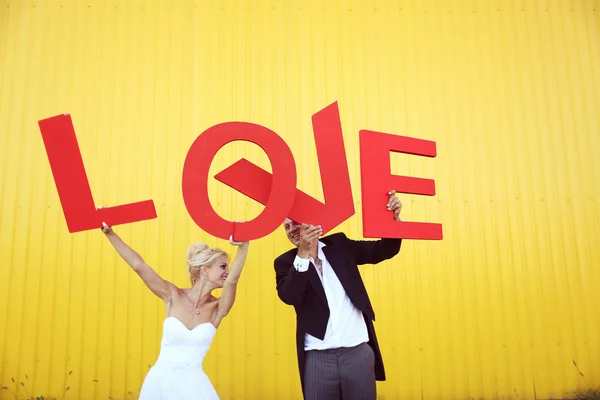 Novia y novio sosteniendo grandes cartas de amor — Foto de Stock