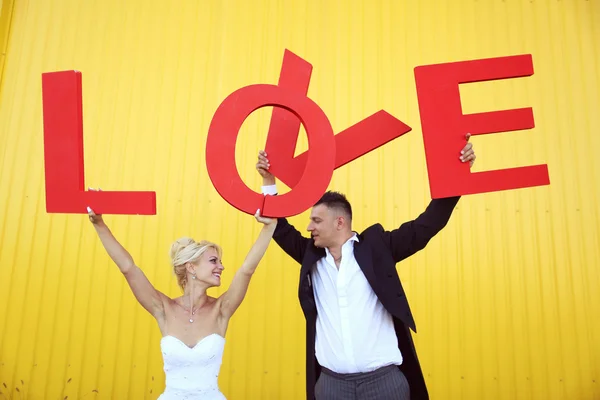 Bride and groom holding big LOVE letters — Stock Photo, Image