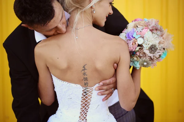 Groom kissing his bride on shoulders — Stock Photo, Image