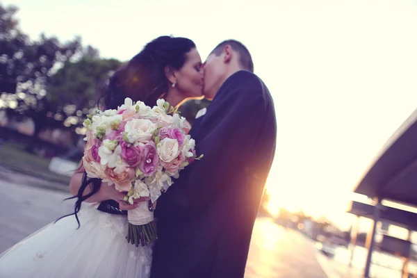 Brudparet kysser vid solnedgången — Stockfoto