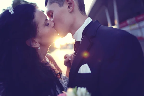 Nevěsta a ženich líbat při západu slunce — Stock fotografie