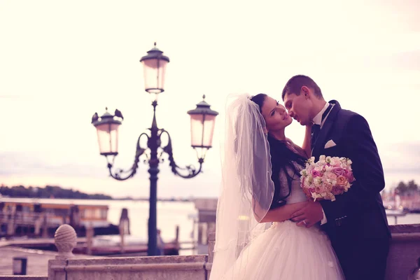 Bride and groom kissing near street lights — Stock Photo, Image