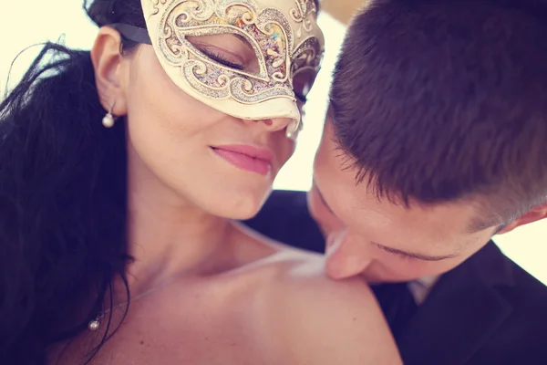 Bräutigam küsst seine Braut. Braut mit venezianischer Maske — Stockfoto