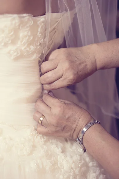 Mãos de mãe ajudando a noiva com o vestido de noiva — Fotografia de Stock