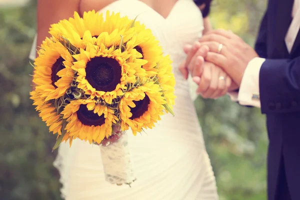 Mãos de uma noiva e noivo segurando buquê de girassol — Fotografia de Stock