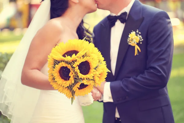 Τα χέρια της ένα νύφης και του γαμπρού κρατώντας την ανθοδέσμη με ήλιους — Φωτογραφία Αρχείου