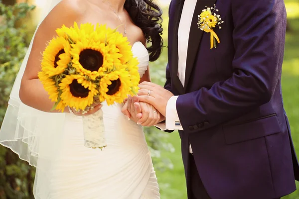 Handen van een bruid en bruidegom houden zonnebloem boeket — Stockfoto