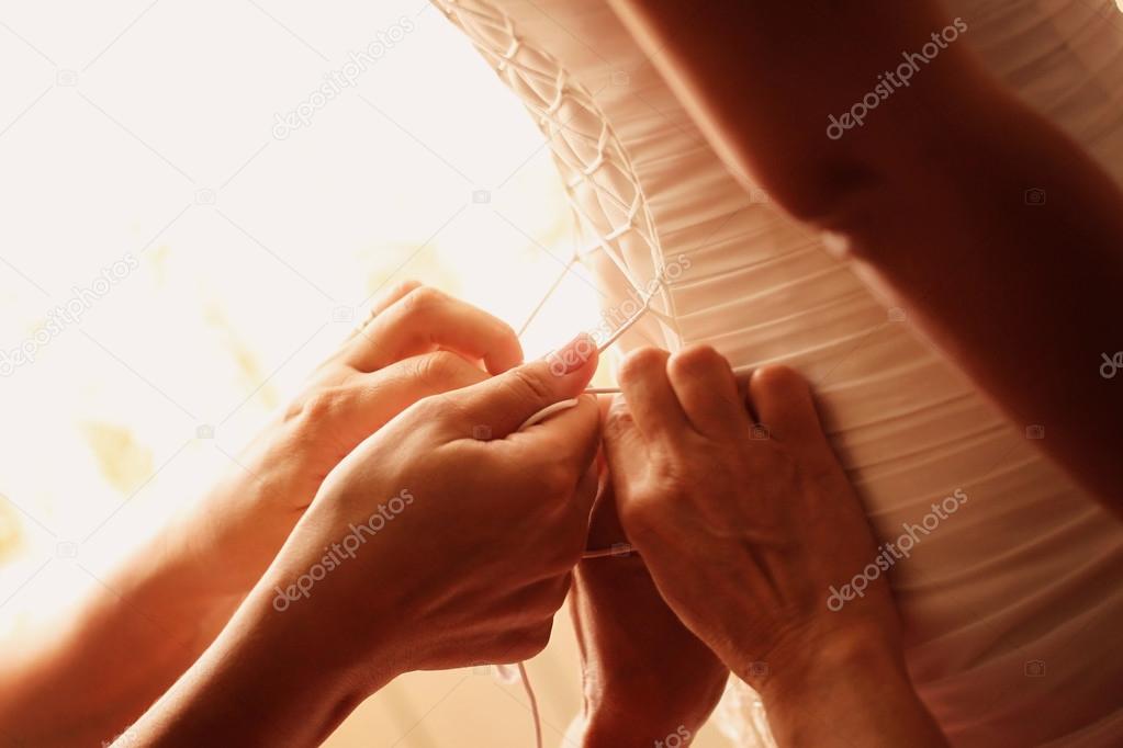 Hands helping the bride with her wedding dress