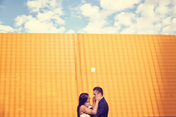 Bride and groom on yellow wall — Stock Photo, Image