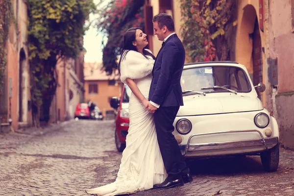 Bruid en bruidegom op straat, in de buurt van oude auto — Stockfoto