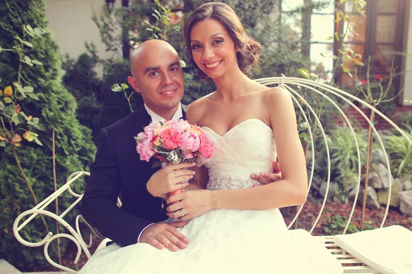 Bride and groom on white bench — Stock Photo, Image