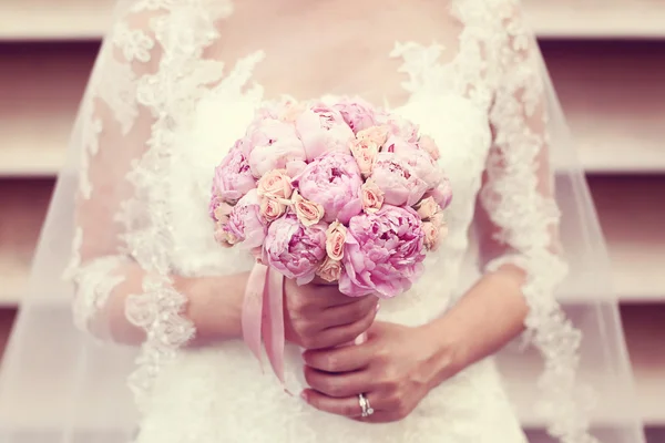 Mãos de uma noiva segurando buquê de peônias — Fotografia de Stock