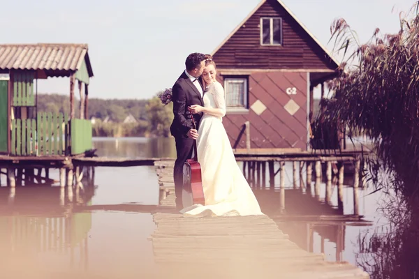 Наречений і наречений на дерев'яному мосту біля озера — стокове фото