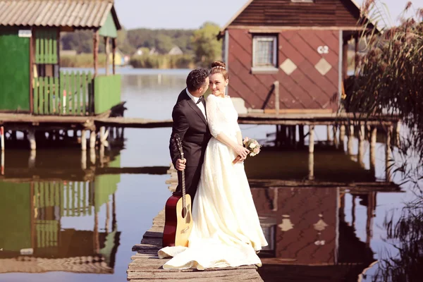 Bruid en bruidegom op een houten brug in de buurt van lake — Stockfoto