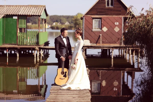 Bride and groom on a wooden bridge near lake — Stock Photo, Image