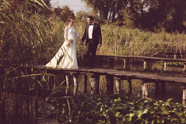 Bride and groom on wooden bridge — Stock Photo, Image