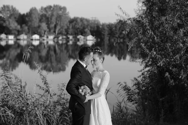 Black and white photograph of a bride and groom near lake — Stock Photo, Image
