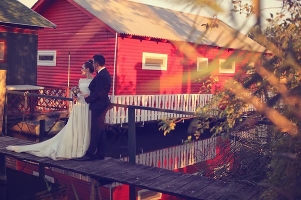 Bride and groom near red house — Stock Photo, Image