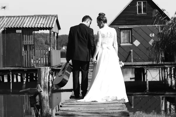 Bride and groom on wooden bridge near lake — Stock Photo, Image