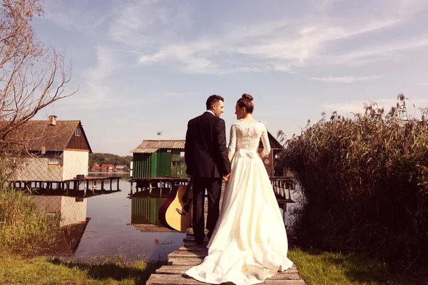 Bride and groom on wooden bridge near lake — Stock Photo, Image